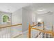 Upstairs hallway with white and wooden railing, decorative pendant, and bright natural light at 1011 Master Gunner Ct, Indian Trail, NC 28079
