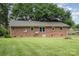 The backyard shows a well-maintained lawn, a brick house, and a metal roof with a fire pit and mature trees at 102 Erwin St, Chester, SC 29706