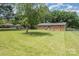 Large backyard features lush green grass, mature trees, and the rear of a brick house with a metal roof at 102 Erwin St, Chester, SC 29706