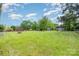 Expansive backyard featuring multiple sheds and a fire pit surrounded by a fenced yard under a blue sky at 102 Erwin St, Chester, SC 29706