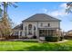 Expansive backyard featuring a white brick home, manicured lawn, fireplace, and screened-in porch at 107 Waterhouse Ct, Mooresville, NC 28117