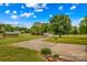 Sprawling green yard with a shed, driveway, and a view of neighboring houses against a blue sky with scattered clouds at 1260 Summer Ln, Salisbury, NC 28146