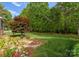 Serene backyard featuring lush landscaping, a manicured lawn, and mature trees, ideal for relaxation and outdoor enjoyment at 174 Buffalo Creek Dr, Statesville, NC 28677