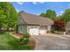 View of a detached garage with white doors, surrounded by lush greenery, and a paved driveway at 174 Buffalo Creek Dr, Statesville, NC 28677