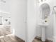 Elegant powder room featuring a pedestal sink, round mirror, and stylish finishes with wood-look floors at 2123 Gemway Dr, Charlotte, NC 28216
