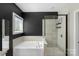 Bright bathroom showcasing a soaking tub with a large window and a glass-enclosed shower with tiled walls at 2214 Laurens Dr, Concord, NC 28027