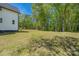 A spacious backyard features a white home and mature trees providing plenty of shade at 5028 Lewis Rd, Gastonia, NC 28052