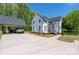 Bright white farmhouse has a covered car port and extra concrete parking spot on a large green lawn at 5028 Lewis Rd, Gastonia, NC 28052