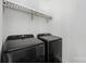 Modern laundry room featuring front loading black washer and dryer and a storage rack above at 5028 Lewis Rd, Gastonia, NC 28052