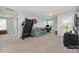Spacious bonus room featuring a comfortable blue sofa, work space, and treadmill; perfect for relaxation and recreation at 6040 Fazio Ct, Harrisburg, NC 28075