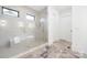 Luxury bathroom featuring large glass shower, bench, and gray tile floors at 632 Dorothy Dr, Charlotte, NC 28203