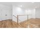 Bright hallway with hardwood floors, white banister, and storage closet at 632 Dorothy Dr, Charlotte, NC 28203