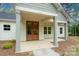 Inviting covered front porch with double wooden doors, columns, and meticulously maintained landscaping at 108 Woodwinds St, Locust, NC 28097
