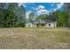 Charming, light colored one-story home with a manicured lawn and surrounded by mature trees at 108 Woodwinds St, Locust, NC 28097