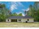 Rear exterior of a light colored home with a well-maintained lawn and trees in the background at 108 Woodwinds St, Locust, NC 28097