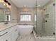 A bright bathroom features a freestanding tub, a glass shower enclosure, and neutral colors at 13237 Fremington Rd, Huntersville, NC 28078