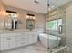 A bright bathroom features dual sinks, a freestanding tub, and a glass shower enclosure at 13237 Fremington Rd, Huntersville, NC 28078