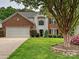 Charming two-story brick home featuring a lush green lawn, well-maintained landscaping and a two car garage at 13237 Fremington Rd, Huntersville, NC 28078