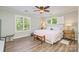 Bedroom featuring two windows with plantation shutters, a ceiling fan, and hardwood flooring at 18524 Mizzenmast Ave, Cornelius, NC 28031