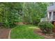 Lush backyard with manicured lawn, mature trees, and a charming swing set in the distance at 202 Whitmyre Ct, Fort Mill, SC 29715