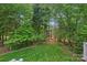 Lush backyard view featuring mature trees and manicured lawn with a small fence at 202 Whitmyre Ct, Fort Mill, SC 29715