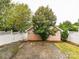 View of backyard garage bordered by a white fence and lush trees providing shade and privacy at 240 Faust Rd, Davidson, NC 28036