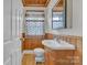 Cozy half-bathroom with wood paneling, pedestal sink, and vintage-style decor at 3101 Hickory Hwy, Statesville, NC 28677