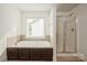 Bathroom with a white drop-in tub with brown paneling, and a glass-enclosed shower at 4015 Amber Leigh Way Dr, Charlotte, NC 28269