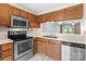 Kitchen showcasing a stainless steel microwave, oven, and sink with wood cabinetry at 407 Eastwood Dr, Salisbury, NC 28146
