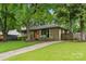 Well-maintained ranch-style home with an orange front door, landscaped yard, and a long driveway at 513 Inwood Dr, Charlotte, NC 28209