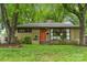 Charming ranch-style home with an orange front door, landscaped yard, mature trees, and black framed windows at 513 Inwood Dr, Charlotte, NC 28209