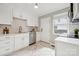 Modern white kitchen with stainless steel appliances, herringbone backsplash, and tile flooring at 513 Inwood Dr, Charlotte, NC 28209