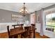 A formal dining room is filled with natural light, showcasing hardwood floors, wainscoting, and decorative chandelier at 728 Palmers Pl, Rock Hill, SC 29730