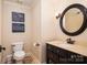 Charming powder room with a marble countertop, dark wood cabinetry, round mirror, and nautical wall art at 8028 Water View Dr, Belmont, NC 28012