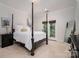 Bedroom with unique four poster bed design, neutral carpet and walls, and window with wooded outdoor views at 8028 Water View Dr, Belmont, NC 28012