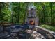 Inviting stone fireplace with outdoor seating in a lush, wooded backyard setting at 8028 Water View Dr, Belmont, NC 28012