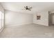 Large living room with neutral walls, plush carpet, a ceiling fan, and view into the kitchen at 8177 Millwright Ln, Charlotte, NC 28277