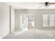 Bright living room with gray walls, plush carpet, ceiling fan, and doors to a private deck at 8177 Millwright Ln, Charlotte, NC 28277