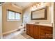 Neutral colored bathroom featuring a wood vanity with light counter, decorative mirror, and tiled floor at 8239 Victoria Lake Dr, Waxhaw, NC 28173