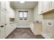 Well-lit laundry room featuring granite countertops, white cabinets and trim, a window and dark tile flooring at 8239 Victoria Lake Dr, Waxhaw, NC 28173