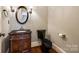 Quaint powder room featuring wood floors, decorative vanity, black toilet and round mirror at 8239 Victoria Lake Dr, Waxhaw, NC 28173