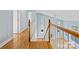Bright hallway features hardwood floors and a white staircase with beautiful natural wood banisters at 9066 Tulagi Ct, Tega Cay, SC 29708