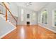 Spacious living room with gleaming hardwood floors, fireplace, staircase, tall windows, and natural light at 9066 Tulagi Ct, Tega Cay, SC 29708