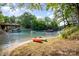 Scenic waterfront view with kayaks on the beach, docks, a boat, and lush trees under a sunny blue sky at 9066 Tulagi Ct, Tega Cay, SC 29708