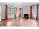 Living room featuring fireplace, hardwood floors, three large windows with curtains, and white trim at 920 Queens Rd, Charlotte, NC 28207