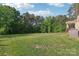 Wide backyard view featuring a manicured lawn and natural treeline in the distance at 1004 Princesa Dr, Matthews, NC 28104