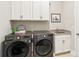 Well-equipped laundry room featuring modern washer and dryer, sink with granite countertop, and storage cabinets at 1004 Princesa Dr, Matthews, NC 28104