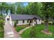 Aerial view of a charming single-story home with a lush lawn, mature trees, and a brick walkway leading to the entrance at 1118 Crestbrook Dr, Charlotte, NC 28211