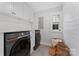 Modern laundry room with front loading washer and dryer, white cabinets, and hexagonal tile flooring at 1118 Crestbrook Dr, Charlotte, NC 28211