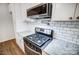 Close-up of a modern kitchen featuring stainless steel appliances, white cabinets, granite countertops, and subway tile backsplash at 1150 Hearth Sw Ln, Concord, NC 28025
